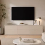 מזנון טלוויזיה בגימור מעוגל בצבע סהרה בהצבה בסלון מתחת לטלוויזיה, עם רמקול מרשל וקערת נחושת על המשטח – מבט קדמי