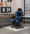 כיסא גיימינג Tesla דגם 7008 בגוון כחול-שחור בפינת עבודה עם שולחן מחשב, שעון דיגיטלי על הקיר וחלון עם וילון פסים