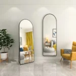 שתי מראות גוף בצורת קשת עם מסגרת מתכת שחורה, אחת עומדת ואחת תלויה על קיר, בסלון עם וילון צהוב - הדמיית חדר