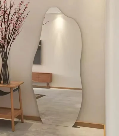 מראת גוף אמורפית ללא מסגרת בצורה גלית מוצמדת לקיר במסדרון, לצד שולחן עץ ופרחים - הדמיית חדר